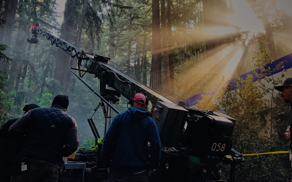 Film production crew operating camera crane on set during large-scale cinematic shoot